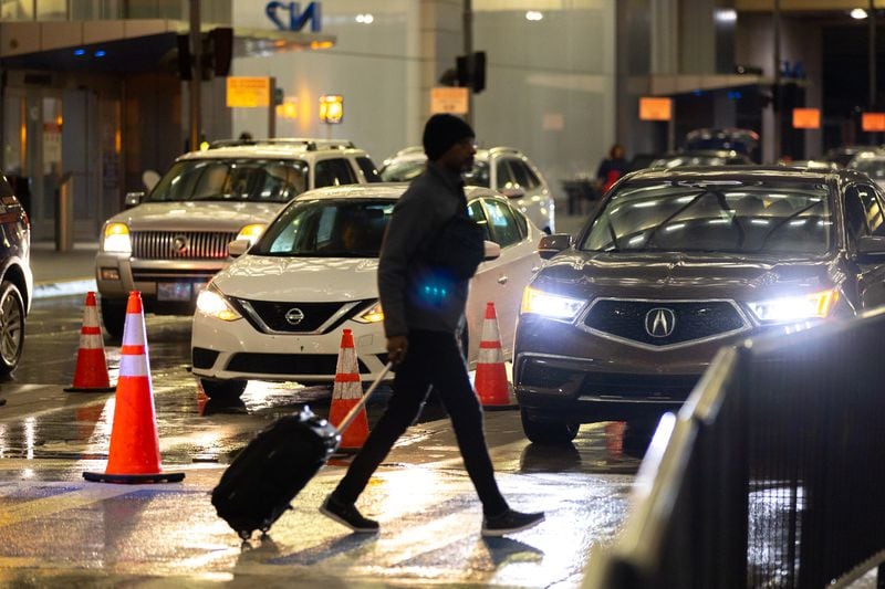 A traveler crosses the road at the Hartsfield-Jackson Atlanta International Airport on Monday, March 27, 2023. (Arvin Temkar / arvin.temkar@ajc.com)