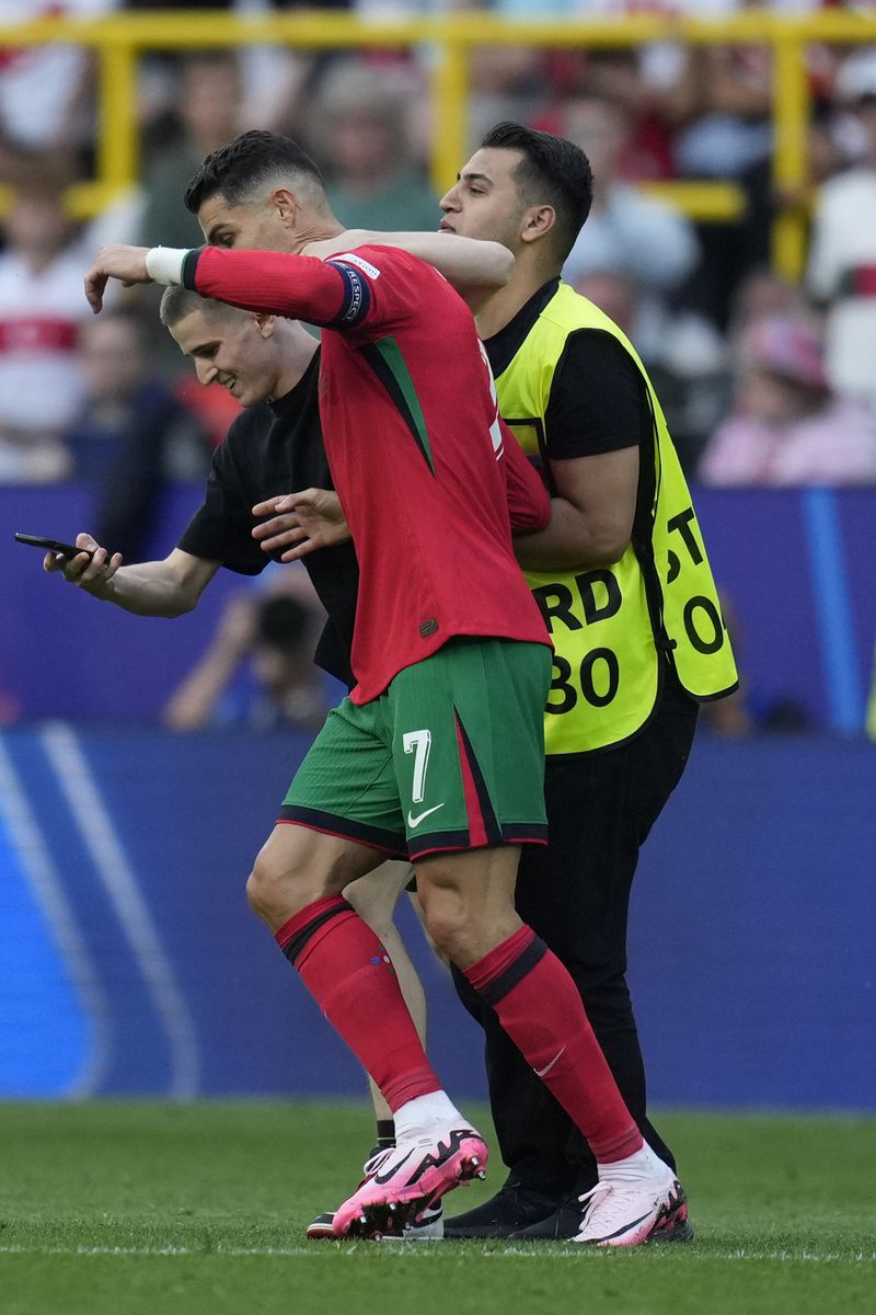 A pitch invader tries to take a selfie with Portugal's Cristiano Ronaldo as a steward moves him out during a Group F match between Turkey and Portugal at the Euro 2024 soccer tournament in Dortmund, Germany, Saturday, June 22, 2024. (AP Photo/Themba Hadebe)