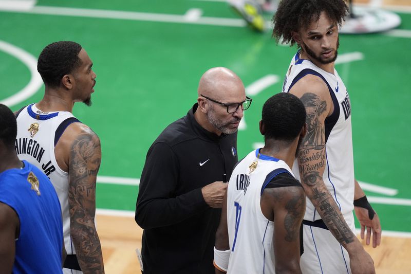 Dallas Mavericks head coach Jason Kidd, center, speaks with guard Kyrie Irving, center right, and center Dereck Lively II, top right, during the first half of Game 5 of the NBA basketball finals against the Boston Celtics, Monday, June 17, 2024, in Boston. (AP Photo/Charles Krupa)