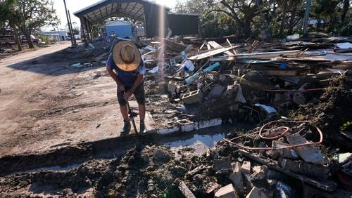 Chris Jordan, maintenance manager for Horseshoe Beach, tries to find a water shutoff valve amid the rubble of the destroyed city hall in the aftermath of Hurricane Helene, in Horseshoe Beach, Fla., Sunday, Sept. 29, 2024. (AP Photo/Gerald Herbert)