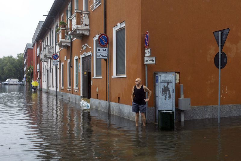 A man stands in floodwater caused by heavy rain in a street in Milan, Italy, Thursday Sept. 5, 2024. (Stefano Porta/LaPresse via AP)