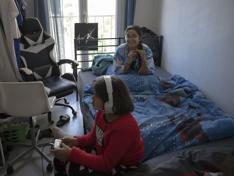 Minane Ould Ibbat, 19, right, watches her brother, Wassim, 11, play video games at their home in Marseille, southern France, Sunday, April 21, 2024. For Minane, as for many French Muslim youth, navigating French culture and her spiritual identity is getting harder. “I ask myself if Islam is accepted in France." (AP Photo/Daniel Cole)