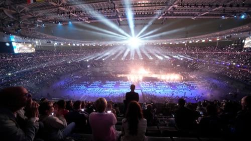 Spectators attend the closing ceremony of the 2024 Paralympics under the rain, Sunday, Sept. 8, 2024, in Paris, France. (AP Photo/Christophe Ena)