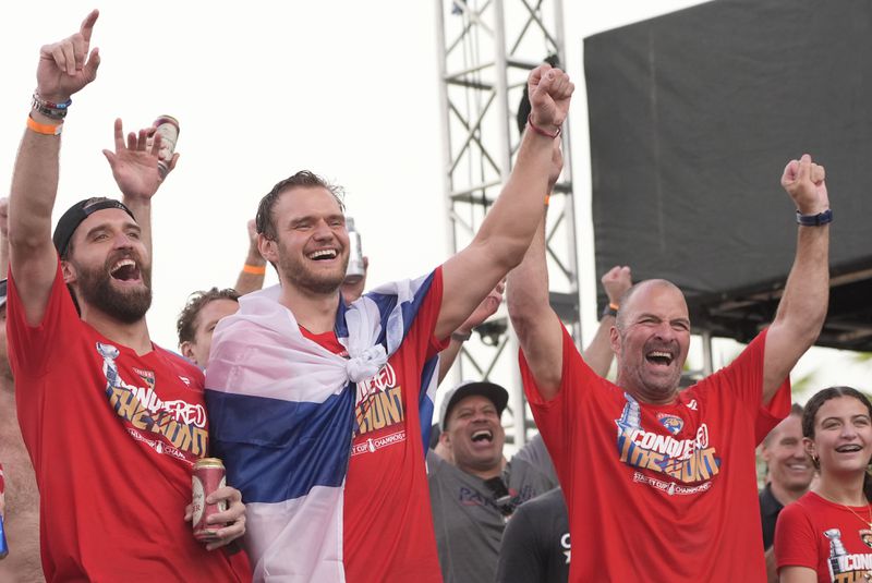 Florida Panthers players Aaron Ekblad, left, Aleksander Barkov, second from left, and general manager Bill Zito, second from right, celebrate after winning the Stanley Cup, by defeating the Edmonton Oilers, during an NHL hockey parade and rally, Sunday, June 30, 2024, in Fort Lauderdale, Fla. (AP Photo/Marta Lavandier)