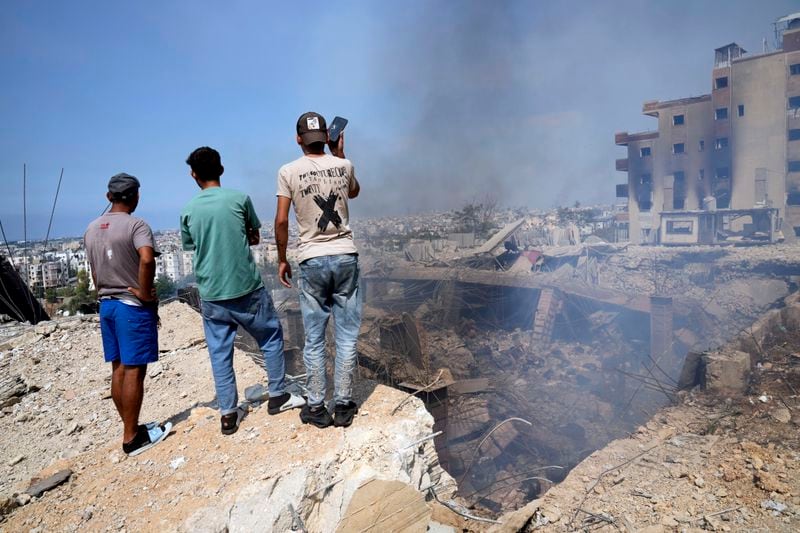 People check a damaged building at the site of an Israeli airstrike in Choueifat, south east of Beirut, Saturday, Sept. 28, 2024. (AP Photo/Hussein Malla)