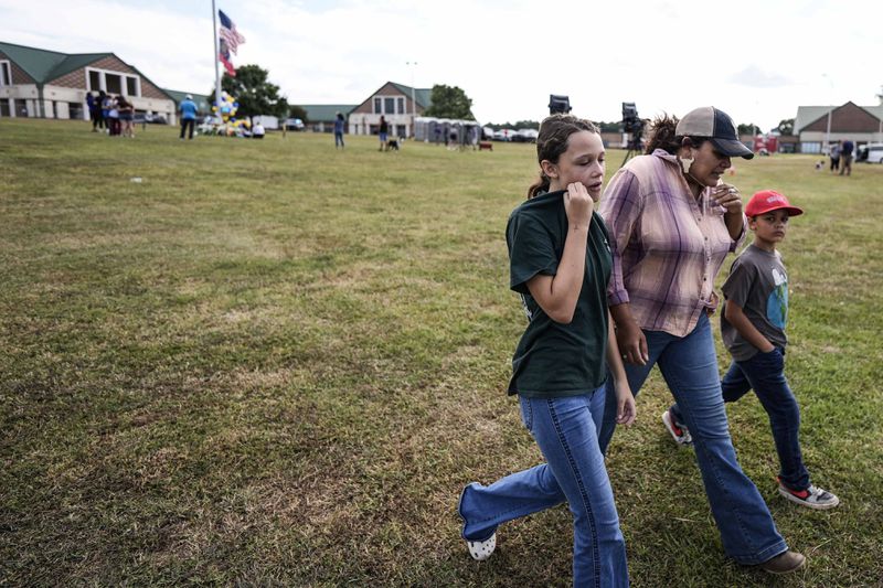 A family leaves a memorial where the American and state of Georgia flags fly half-staff after a shooting Wednesday at Apalachee High School, Thursday, Sept. 5, 2024, in Winder, Ga. (AP Photo/Mike Stewart)