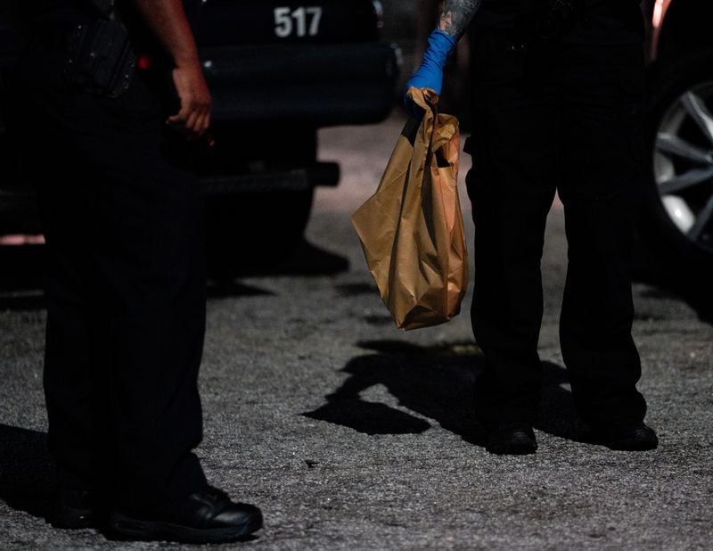 A Fulton County Medical Examiner's Office employee holds a bag containing a human skull found near train tracks in the area of Northside Drive and North Avenue.