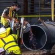 A large 30-inch pipe was seen being lowered into the hole at 11th and West Peachtree Street Tuesday morning, June 4, 2024. According to the city, the Department of Watershed Management was ready to start installing and conducting the remaining steps to restore water service. (John Spink/AJC)
