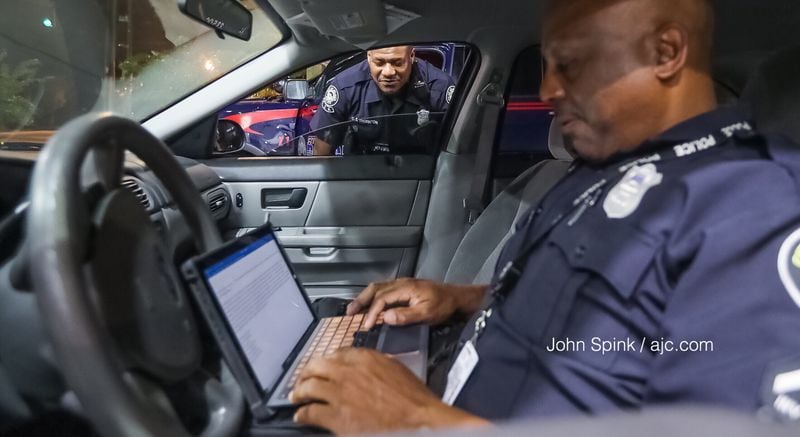 Atlanta police officers C.S. Thonton (left) and D. Terrell work on a report after a Morehouse College student was carjacked early Thursday. Police called the case "pretty heartbreaking," as the student was robbed of his transportation to a relative's funeral back home in Louisiana. JOHN SPINK / JSPINK@AJC.COM