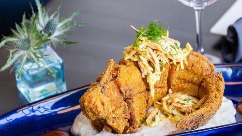 Oreatha's Thai-Southern fusion entree tod mun pla features a whole fried catfish on a bed of riced cauliflower grits, with tamarind hot sauce and curry coleslaw. Ryan Fleisher for The Atlanta Journal-Constitution