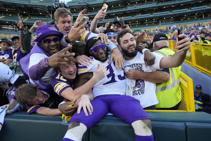 Minnesota Vikings running back Aaron Jones (33) celebrates the team's win after an NFL football game against the Green Bay Packers, Sunday, Sept. 29, 2024, in Green Bay, Wis. (AP Photo/Morry Gash)