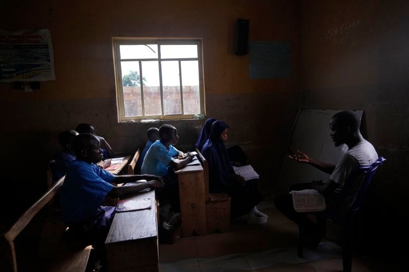 Students of Excellent Moral School attend a lesson in a window-lit classroom in Ibadan, Nigeria, Tuesday, May 28, 2024. Schools like Excellent Moral operate in darkness due to zero grid access, depriving students of essential tools like computers. (AP Photo/Sunday Alamba)