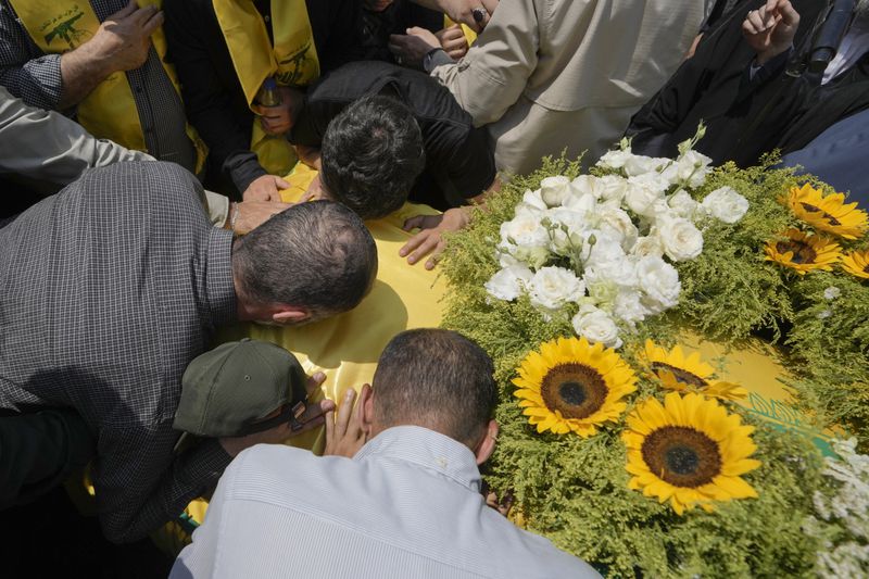 Mourners kiss the coffin of Hezbollah senior commander Taleb Sami Abdullah, 55, known within Hezbollah as Hajj Abu Taleb, who was killed late Tuesday by an Israeli strike in south Lebanon, during his funeral procession in the southern suburbs of Beirut, Lebanon, Wednesday, June 12, 2024. Hezbollah fired a massive barrage of rockets into northern Israel on Wednesday to avenge the killing of the top commander in the Lebanese militant group as the fate of an internationally-backed plan for a cease-fire in Gaza hung in the balance. (AP Photo/Bilal Hussein)