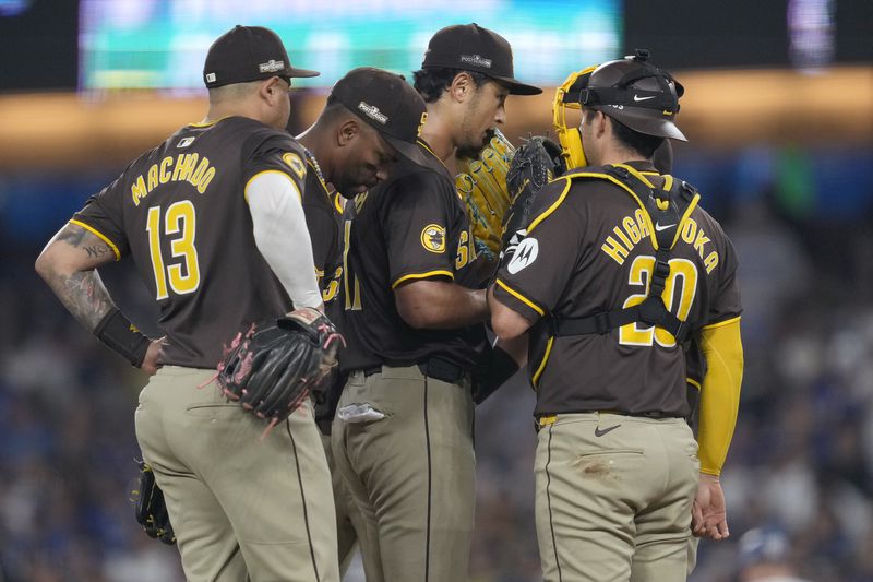 San Diego Padres pitcher Yu Darvish, middle right, talks with third baseman Manny Machado (13), shortstop Xander Bogaerts, middle left, and catcher Kyle Higashioka on the mound during the sixth inning in Game 2 of a baseball NL Division Series against the Los Angeles Dodgers, Sunday, Oct. 6, 2024, in Los Angeles. (AP Photo/Ashley Landis)