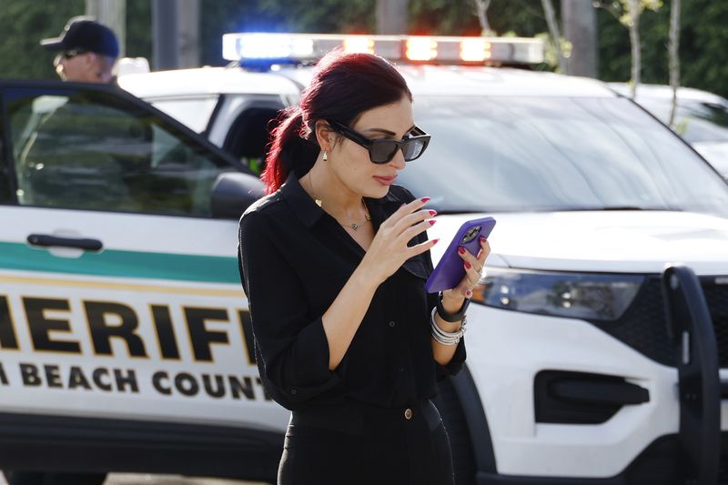 Laura Loomer uses her cell phone near Trump International Golf Club after police closed off the area following the apparent assassination attempt of Republican presidential nominee former President Donald Trump in West Palm Beach, Fla., Sunday, Sept. 15, 2024. (AP Photo/Terry Renna)