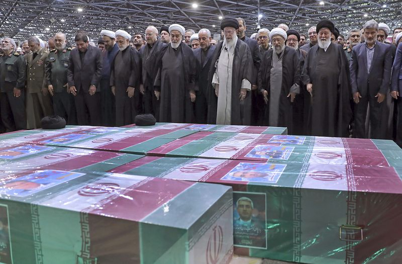 In this photo released by an official website of the office of the Iranian supreme leader, Supreme Leader Ayatollah Ali Khamenei, center right with black turban, leads a prayer over the flag-draped coffins of the late President Ebrahim Raisi and his companions who were killed in a helicopter crash on Sunday in a mountainous region of the country's northwest, at the Tehran University campus, during a funeral ceremony for them in Tehran, Iran, Wednesday, May 22, 2024. Khamenei presided over the funeral Wednesday for the country's late president, foreign minister and others killed in the helicopter crash, as tens of thousands later followed a procession of their caskets through the capital, Tehran. (Office of the Iranian Supreme Leader via AP)