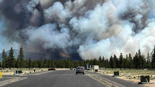 Smoke from a wildfire rises on a road near La Pine, Ore., Tuesday, June 25, 2024. The fire prompted mandatory evacuations in the small town in central Oregon and was growing rapidly in hot, dry conditions. (Jim Pharris via AP)