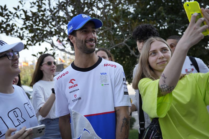 RB driver Daniel Ricciardo of Australia poses for a selfie with fans in the paddock at the Baku circuit, in Baku, Azerbaijan, Thursday, Sept.12, 2024. The Formula One Grand Prix will be held on Sunday. (AP Photo/Sergei Grits)