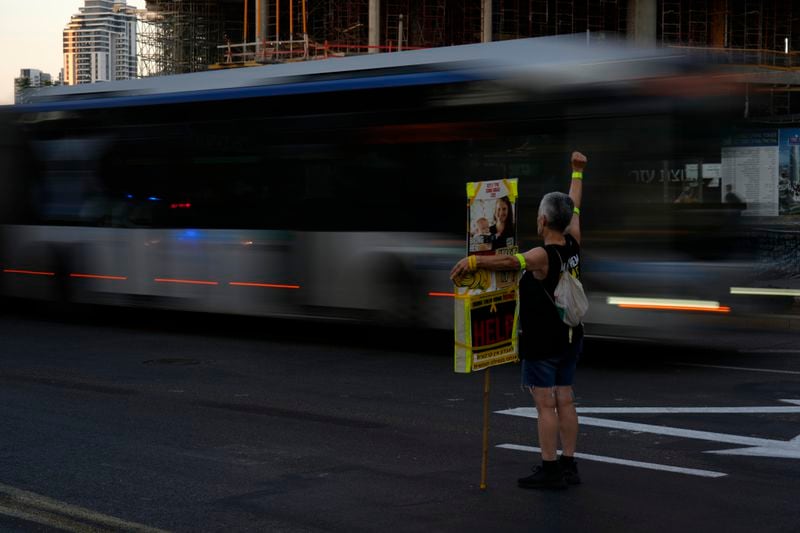 A protester holds a poster showing Shiri Bibas and her child, Kfir, hostages taken with their family by Hamas militants to the Gaza Strip, to honor the memories of six men whose bodies were returned and to call for a deal to release the remaining captives, in Tel Aviv, Tuesday, Aug. 20, 2024. (AP Photo/Ariel Schalit)