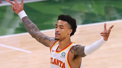 Hawks forward John Collins reacts as Trae Young hits a three pointer during a 116-113 victory over the Milwaukee Bucks in Game 1 of the Eastern Conference Finals Wednesday, June 23, 2021, in Milwaukee.  (Curtis Compton / Curtis.Compton@ajc.com)