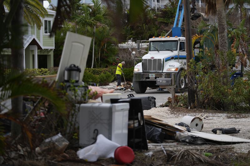 Teams work to clean up debris from Hurricane Helene flooding ahead of the arrival of Hurricane Milton, in Holmes Beach on Anna Maria Island, Fla., Tuesday, Oct. 8, 2024. (AP Photo/Rebecca Blackwell)