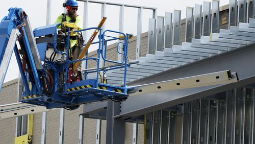 A construction worker maneuvers a lift outside a commercial building site in Mount Prospect, Ill., Tuesday, Aug. 27, 2024. (AP Photo/Nam Y. Huh)