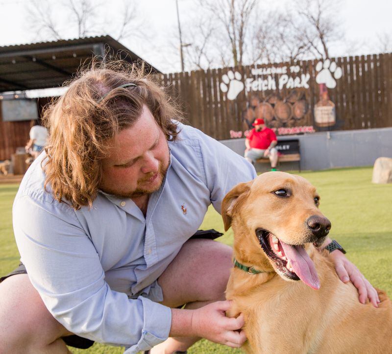 Matt Matuszewski and his yellow lab Murphy play at Fetch Park at Boulevard and DeKalb Ave on Friday,  March 12, 2021.  (Jenni Girtman for The Atlanta Journal-Constitution)