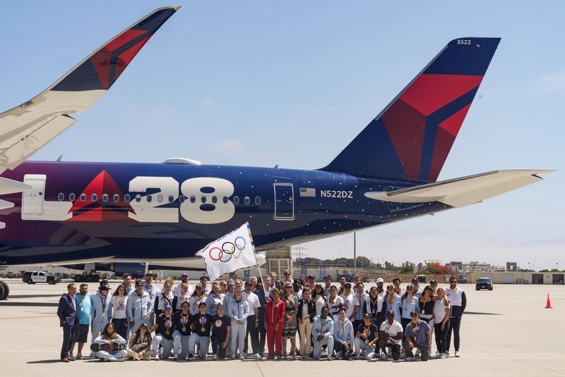 Los Angeles Mayor Karen Bass, Team USA athletes, LA28 organizing committee members and the United States Olympic & Paralympic Committee (USOPC), Delta executives and special guests take a picture with the official Olympic flag at Los Angeles International Airport on Monday, Aug. 12, 2024. (AP Photo/Damian Dovarganes)