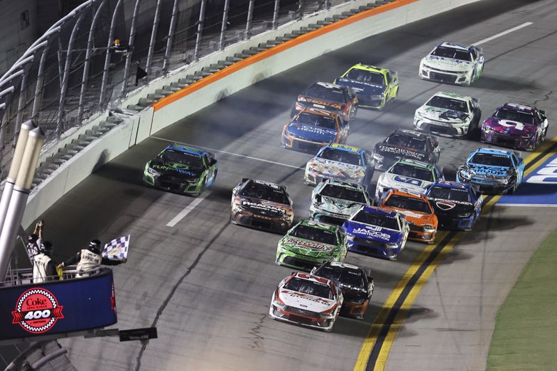 Harrison Burton (21) takes the checkered flag to win a NASCAR Cup Series auto race at Daytona International Speedway, Saturday, Aug. 24, 2024, in Daytona Beach, Fla. (AP Photo/David Graham)