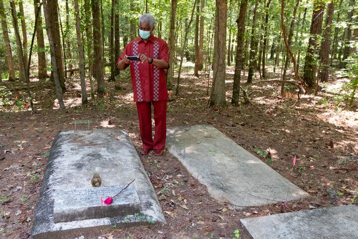 Minister Roosevelt Broadnax takes photos of one of the few marked graves at the Pierce Chapel African Cemetery in Midland, outside of Columbus, on Monday, June 20, 2022. The cemetery was rediscovered in 2019 and work has since been done to clean, document and preserve it. Ben Gray for the Atlanta Journal-Constitution