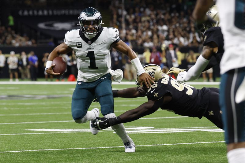 Philadelphia Eagles quarterback Jalen Hurts (1) scrambles past New Orleans Saints defensive end Carl Granderson (96) in the first half of an NFL football game in New Orleans, Sunday, Sept. 22, 2024. (AP Photo/Butch Dill)