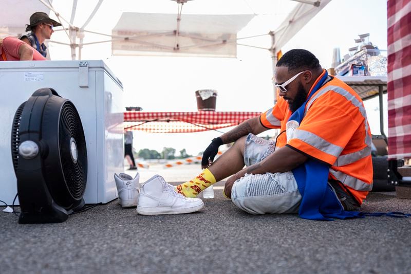 Brian Ford takes to time to cool off by taking off his shoes, drinking water, and sitting in front of a fan as he works the Uncle Scotty's Favorites food concession stand at the Middletown Pride Festival, Friday, June 21, 2024, in Middletown, Ohio. (AP Photo/Carolyn Kaster)