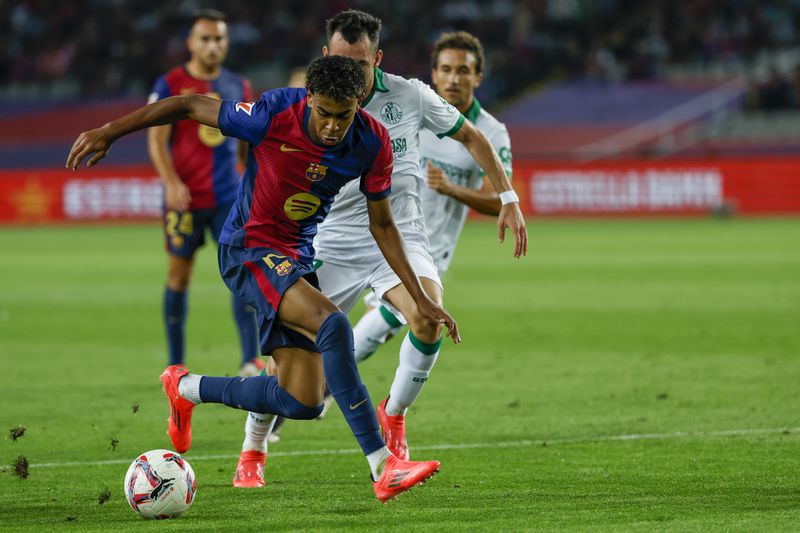 Barcelona's Lamine Yamal, front, duels for the ball with Getafe's Alex Sola during a Spanish La Liga soccer match between Barcelona and Getafe at the Olympic stadium in Barcelona, Spain, Wednesday, Sept. 25, 2024. (AP Photo/Joan Monfort)