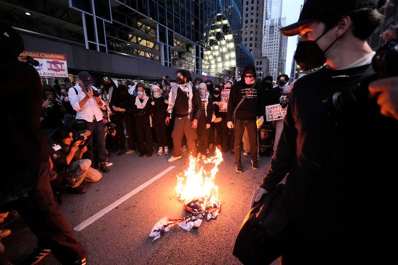 Protesters burn a flag near the Israeli Consulate during the Democratic National Convention Tuesday, Aug. 20, 2024, in Chicago. (AP Photo/Alex Brandon)