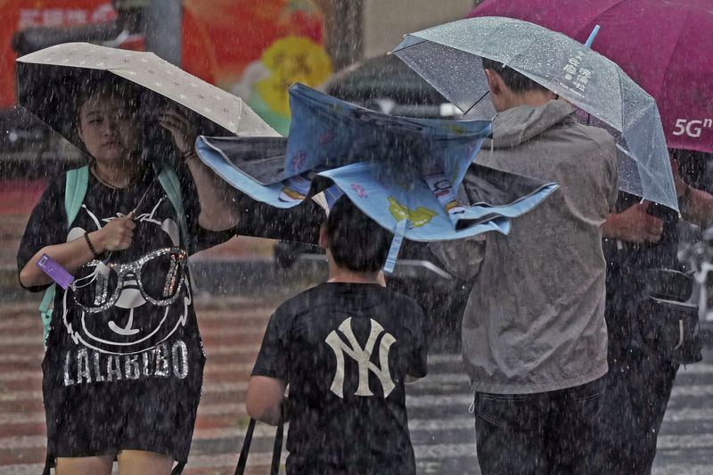 In this photo released by Xinhua News Agency, people brace for rain on a street as Typhoon Bebinca made landfall in Shanghai, China, Monday, Sept. 16, 2024. (Liu Ying/Xinhua via AP)