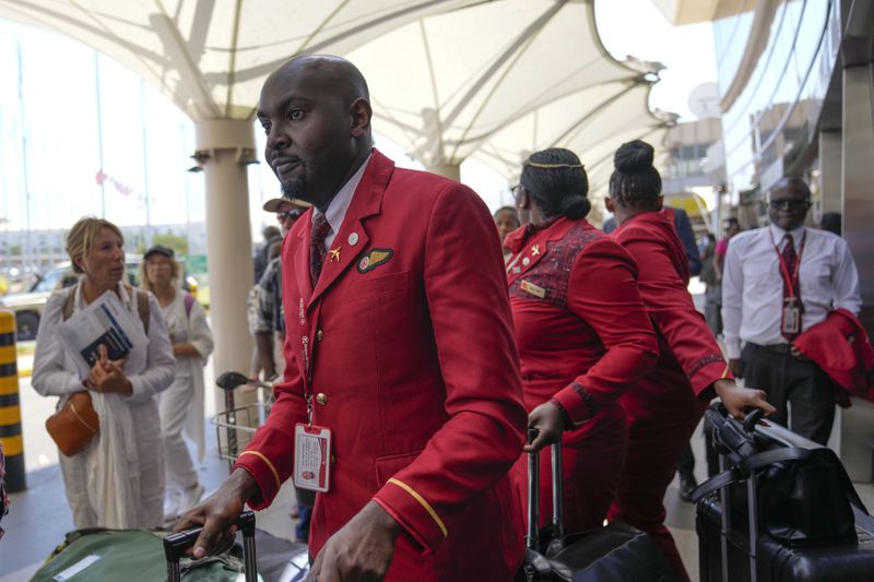 Kenya airways flight attendants queue alongside stranded passengers waiting for their delayed flights out of JKIA airport after flights were grounded following workers’ protesting a planned deal between the government and a foreign investor, in Nairobi, Kenya, Wednesday, Sept. 11, 2024. (AP Photo/Brian Inganga)