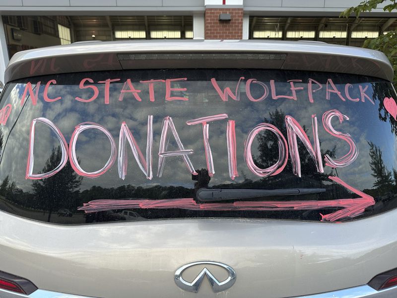 A makeshift sign in a vehicle window helps direct people arriving at a donation drive led by N.C. State defensive end Davin Vann to collect supplies to help Hurricane Helene victims in western North Carolina, Wednesday, Oct. 2, 2024 in Raleigh, N.C. (AP Photo/Aaron Beard)