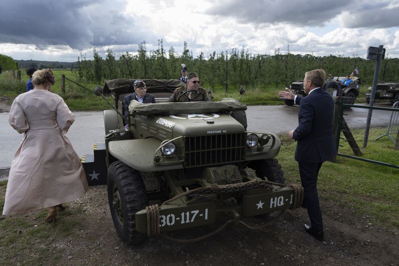 World War II veteran Kenneth Thayer, seated left, is greeted by Dutch King Willem-Alexander and Queen Maxima before the royals joined Thayer in the jeep during a ceremony marking the 80th anniversary of the liberation of the south of the Netherlands in Mesch, Thursday, Sept. 12, 2024. (AP Photo/Peter Dejong, Pool)