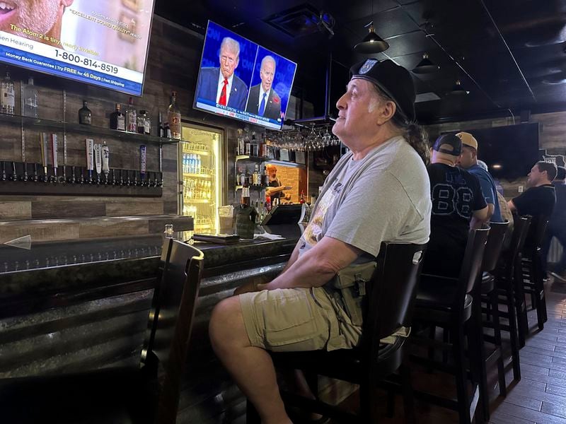 Veteran Hector Mercado, 72, watches the presidential debate in a crowded McAllen, Texas bar Thursday, June 27, 2024. Although he was a Democrat for several years, he switched parties under Reagan. Mercado heard the allegations Biden raised about Trump's derogatory comments about veterans, but it didn't sway his support. "Yea, he said a few things bad about about veterans at one point back in the early days. But now he's saying, no, I back up the veterans and I never had any problems with him. I got a raise in my VA disability when Trump was president," Mercado said, standing by his choice. (AP Photo/Valerie Gonzalez)