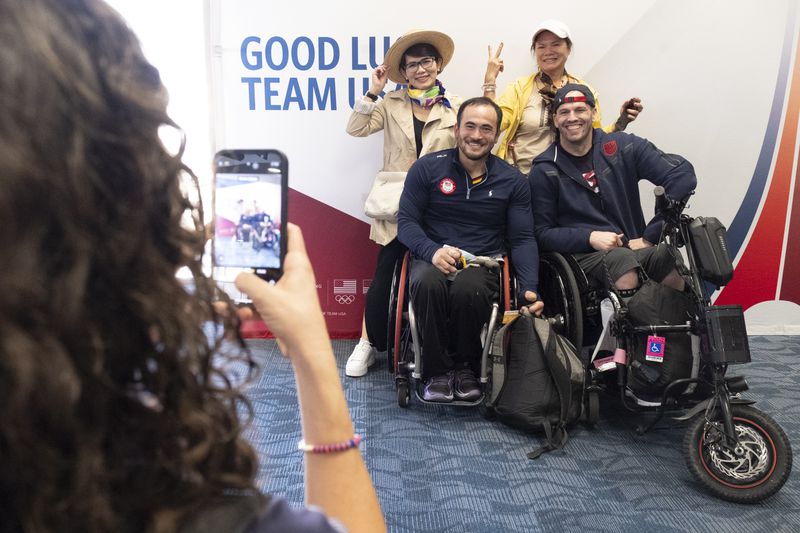 Sisters Luan, left, and Mylinh Huynh pose for a photo with USA Paralympic wheelchair rugby team members Chuck Aoki, left, and Josh Wheeler before they all boarded a Delta flight in Atlanta headed for Paris on Tuesday, Aug. 20, 2024. The Huynh sisters weren’t going to Paris to attend the games, but were excited to meet some of the athletes. (Ben Gray / Ben@BenGray.com)