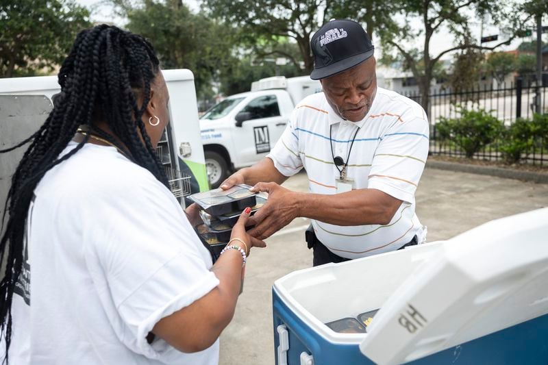 Tracey Hill and Napier Williams move hot meals from a cooler into a Meals on Wheels delivery truck, Friday, July 12, 2024, in Houston. They have many clients who rely on food delivery but also human connection provided by Meals on Wheels employees. (AP Photo/Annie Mulligan)