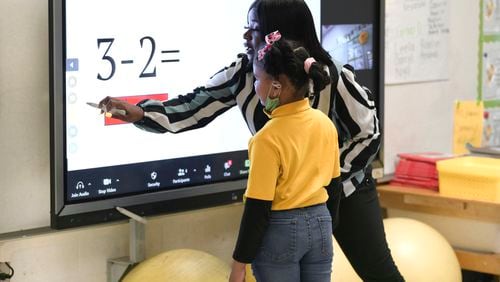 A kindergarten teacher helps a Georgia student with a math problem on Wednesday, April 19, 2022. Nationally, math scores fell to new lows on the National Assessment of Educational Progress, leading to calls for renewed efforts to counter the ill effects of the pandemic on student learning. (Natrice Miller / natrice.miller@ajc.com)