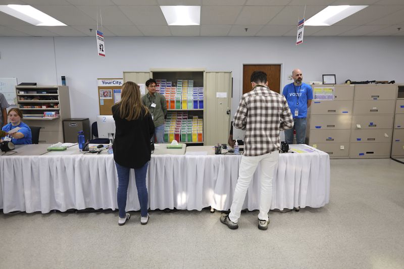 Early voters get their ballots at the City of Minneapolis early voting center, Friday, Sept. 20, 2024, in Minneapolis, Minn. (AP Photo/Adam Bettcher)