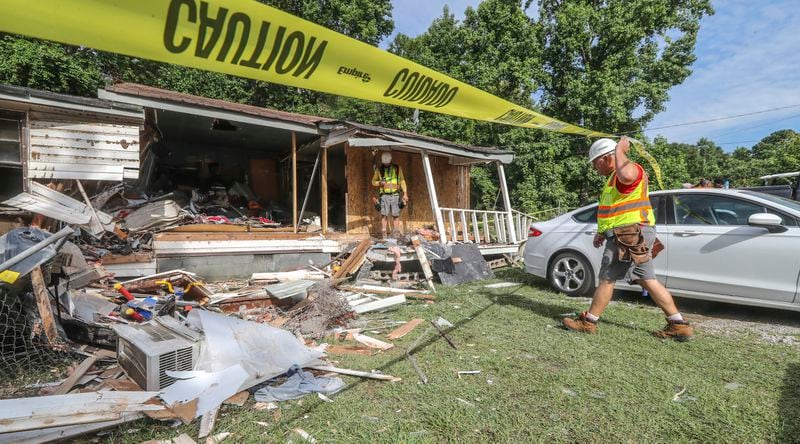 Major Oliver (right) and Adam Wall with 1-800 Board Up work on the home where a woman is dead after a vehicle crashed into her house following a police pursuit that reached speeds over 130 mph on June 30.


