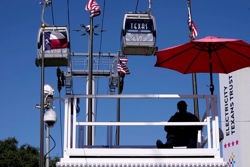 A Dallas police officer, sitting bottom right, watches activity from a high platform as sky cabs make their way past at the State Fair of Texas in Dallas, Friday, Sept. 27, 2024. (AP Photo/Tony Gutierrez)