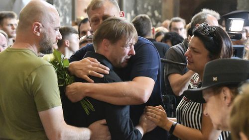 Friends hug Yaroslav Bazylevych during the funeral service for his family in the Garrison Church in Lviv, Ukraine, Friday, Sept. 6, 2024. Bazylevych's wife Yevgenia and their three daughters - Darina, 18, Emilia, 7, and Yaryna, 21 - were killed in Wednesday's Russian missile attack. (AP Photo/Mykola Tys)