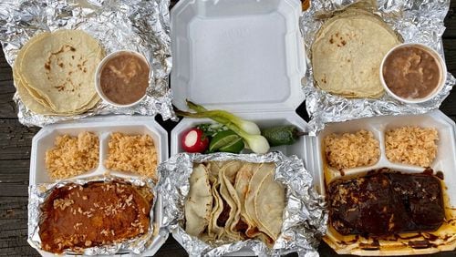 This feast of takeout dishes from Taqueria La Oaxaquena in Jonesboro includes: chile rellenos; a plate of four tacos; and chicken mole. Wendell Brock for The Atlanta Journal-Constitution