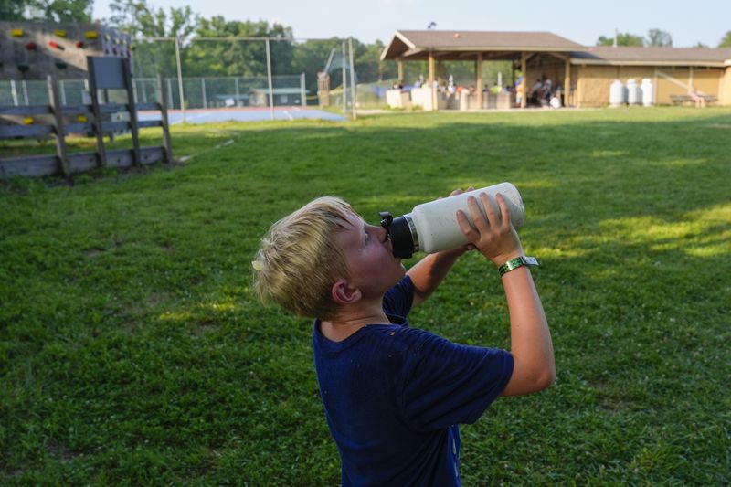 A camper drinks water, Thursday, June 20, 2024, at YMCA Camp Kern in Oregonia, Ohio. As the first heat wave of the season ripples across the U.S., summer camps are working to keep their children cool while still letting the kids enjoy being outside with nature. (AP Photo/Joshua A. Bickel)