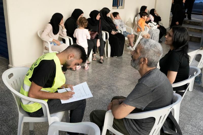 A Lebanese couple fleeing the Israeli airstrikes in the south, register their names as they arrive at a school turned into a shelter in Beirut, Monday, Sept. 23, 2024. (AP Photo/Bilal Hussein)