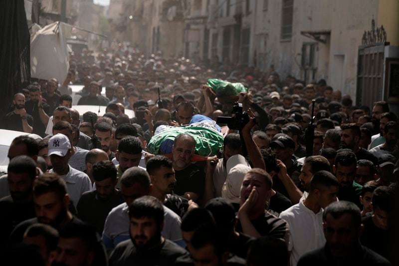 Mourners march during a funeral with the bodies of Palestinians Ahmed Abu Arra from the town of Aqaba, left, and Raafat Dawasa from the town of Silat Al-Harithiya, both draped in the Hamas flag and killed in an Israeli strike in the Jenin refugee camp, in the West Bank city of Jenin, Sunday, Aug. 18, 2024. Israel's military said Saturday it struck a "terrorist cell" in Jenin. The Palestinian health ministry there said two bodies were taken to a government hospital; Hamas claimed the two men as commanders in its military wing. (AP Photo/Majdi Mohammed)